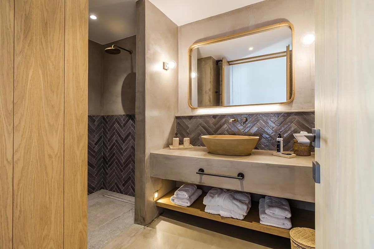 Bathroom with modern basin, large mirror, and dark herringbone tiles at Eliamos in Kefalonia, Greece.