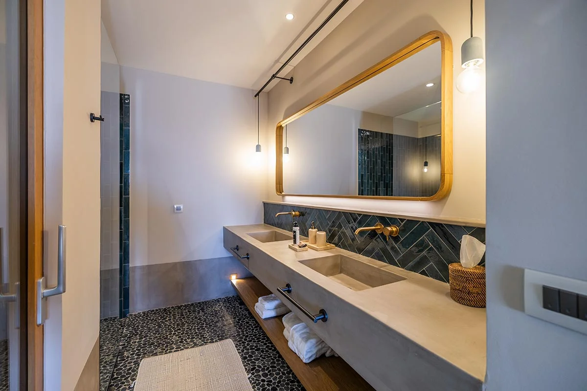 Bathroom with long double concrete vanity, gold taps, and chevron tiling at Eliamos resort in Kefalonia.