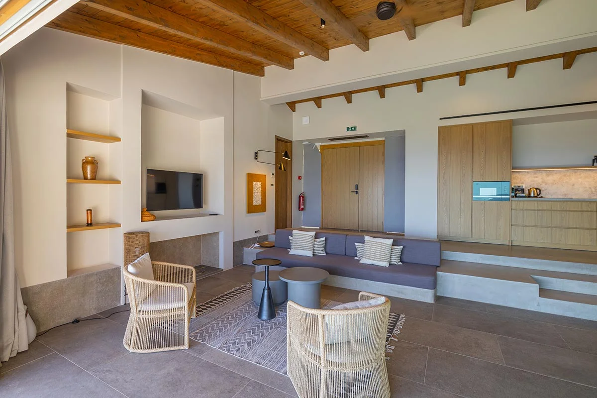 Modern living room at Eliamos, Kefalonia with wooden ceiling, built-in sofa and open-plan kitchen.