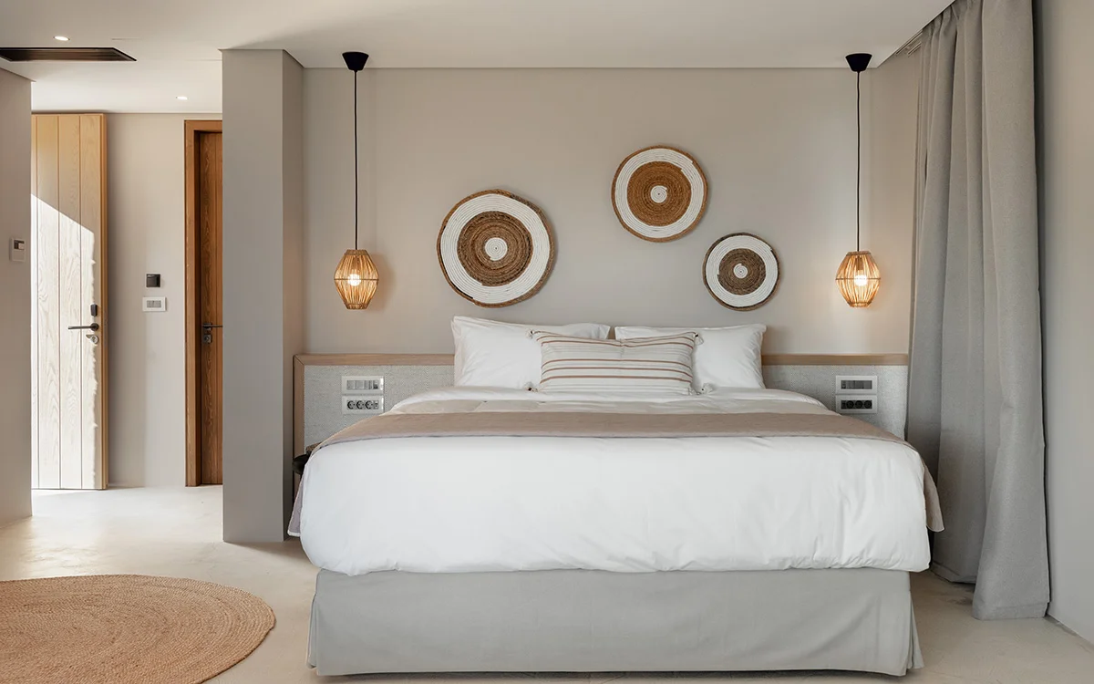 Neutral-toned Eliamos bedroom in Kefalonia with hanging lights, woven wall decor and natural textures.