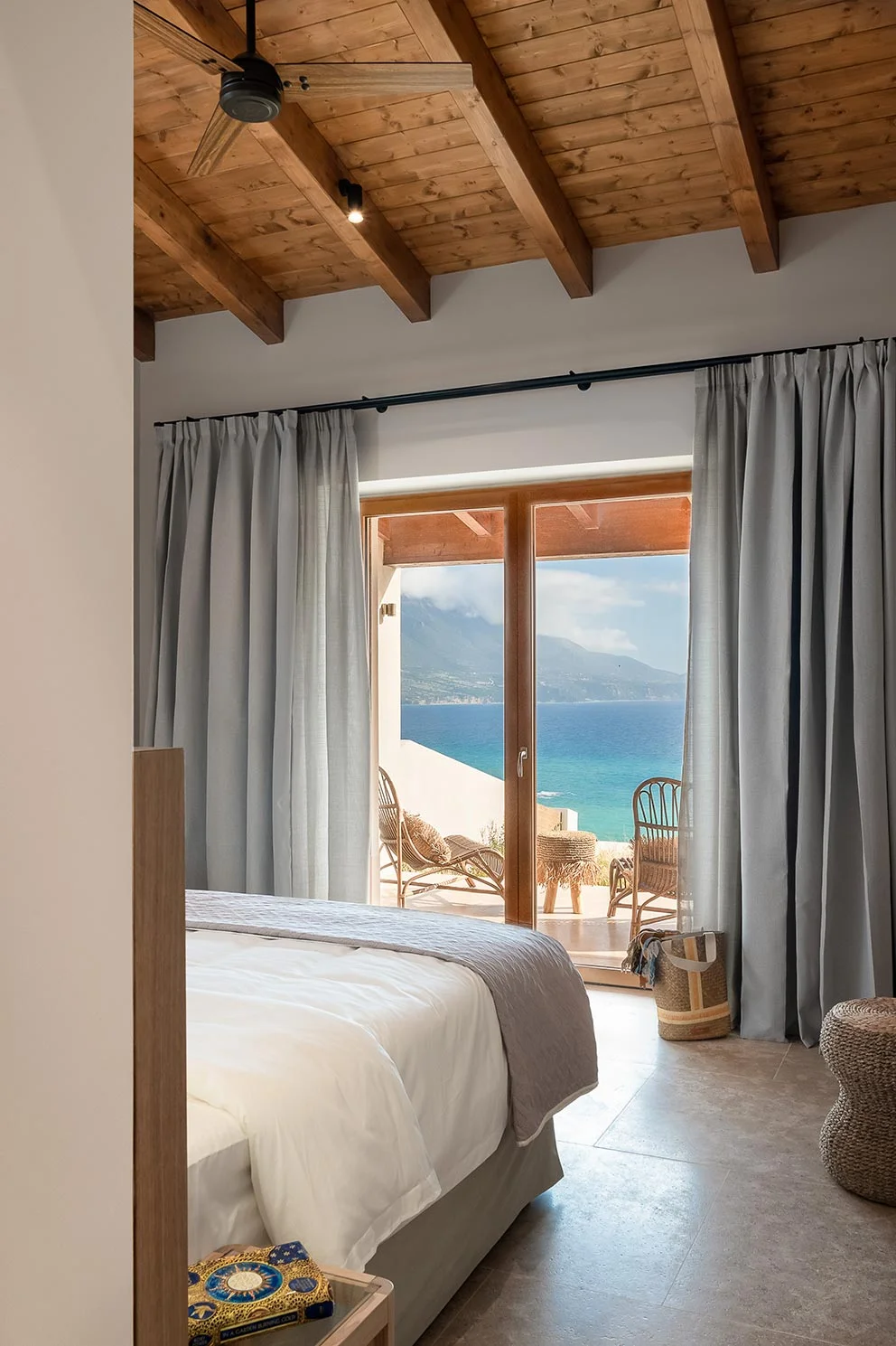Seaside bedroom with vaulted wooden ceiling and terrace view of the Ionian Sea at Eliamos in Kefalonia.