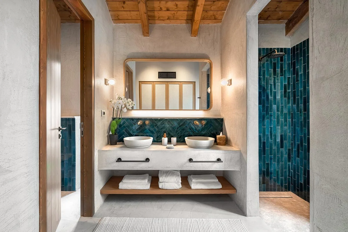 Bathroom with dual sinks, green tiled shower, and exposed wood ceiling at Eliamos in Kefalonia, Greece.