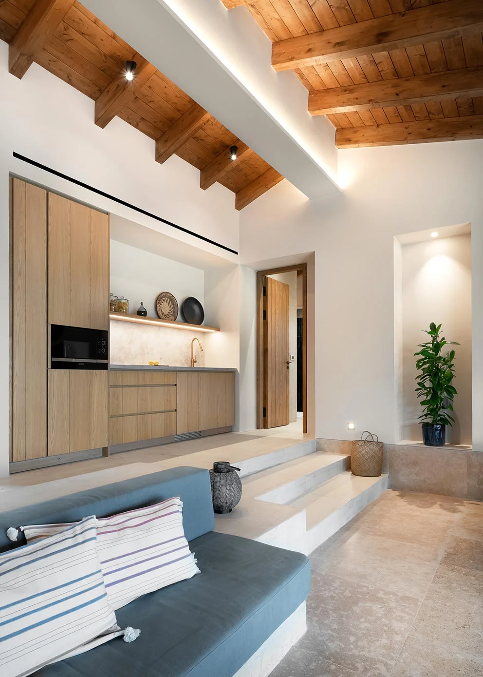 Open-plan kitchen and living space with exposed beam ceiling and steps down to seating at Eliamos in Kefalonia.