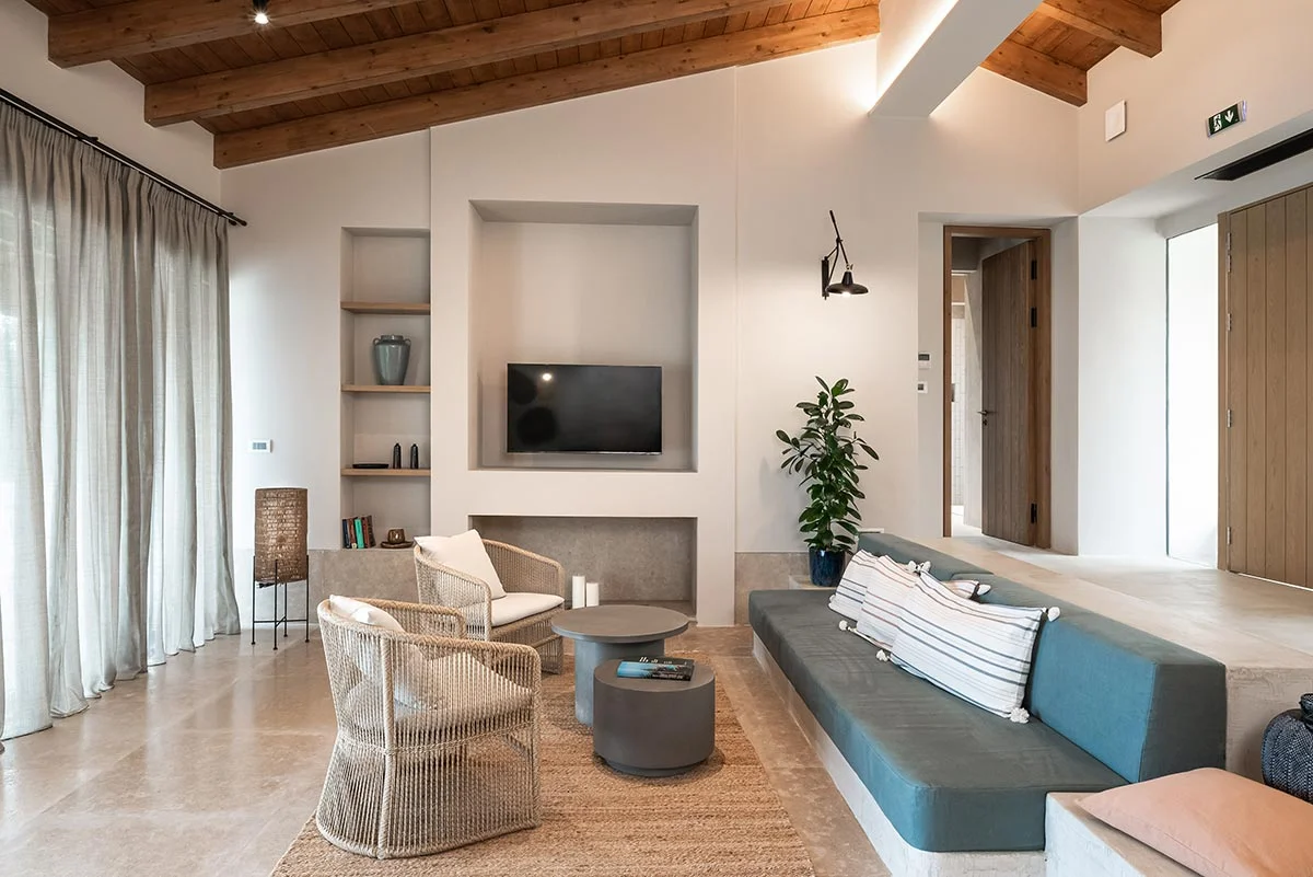 Spacious living area with modern built-in TV wall, neutral seating, and natural materials at Eliamos villas in Kefalonia.