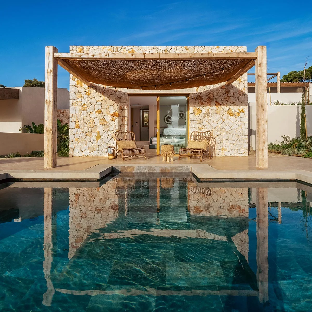 Private pool outside an Eliamos stone suite in Kefalonia with shaded veranda and rattan lounge chairs.