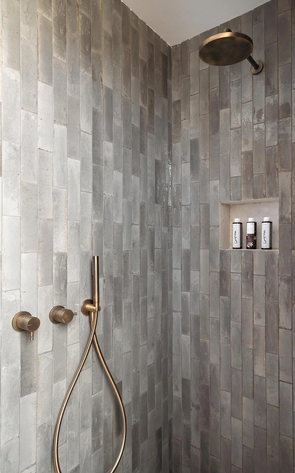 Walk-in shower with grey vertical tiles and brushed brass fixtures at Eliamos in Kefalonia, Greece.