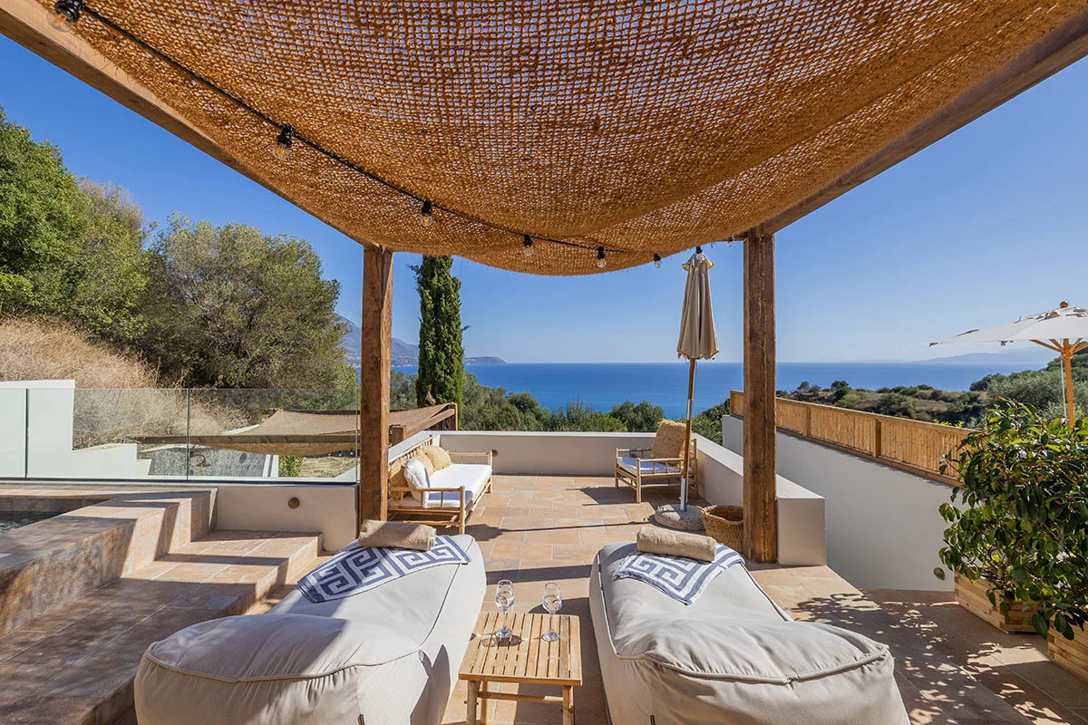 Terrace with sun loungers, sea view, and shaded pergola overlooking Ionian Sea at Eliamos resort in Kefalonia.