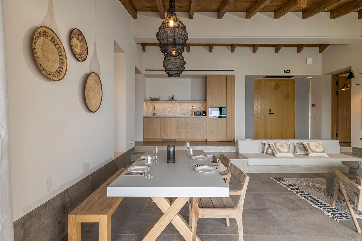 Dining and kitchen area with natural wood and pendant lights in an open-plan villa at Eliamos luxury resort in Kefalonia.